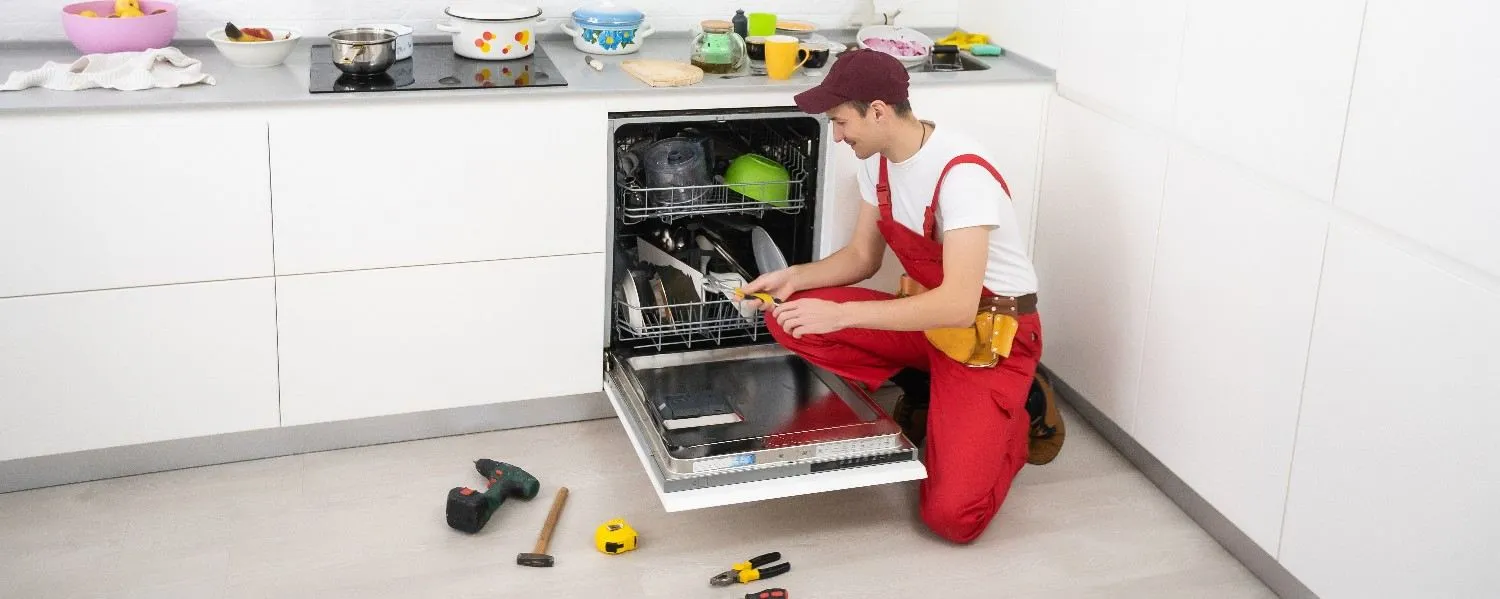 Technician repairing an open dishwasher in a kitchen